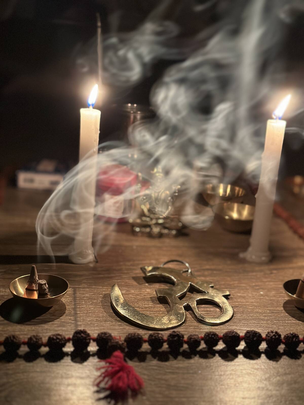 Ein Altar mit Kerzen, Räucherwerk, einem Om aus Messing und einer Mala